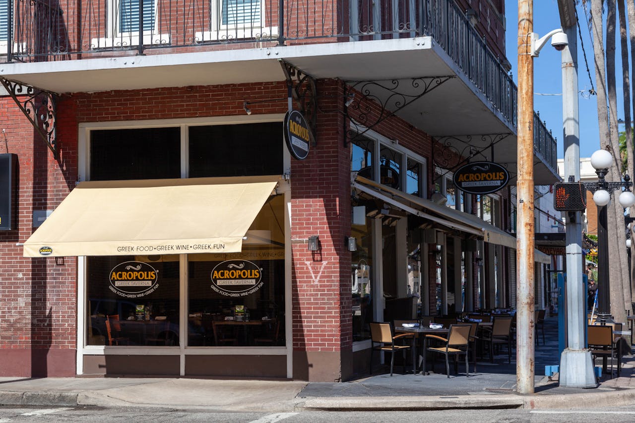 Cozy Greek restaurant with outdoor seating in a brick building, perfect for urban dining.